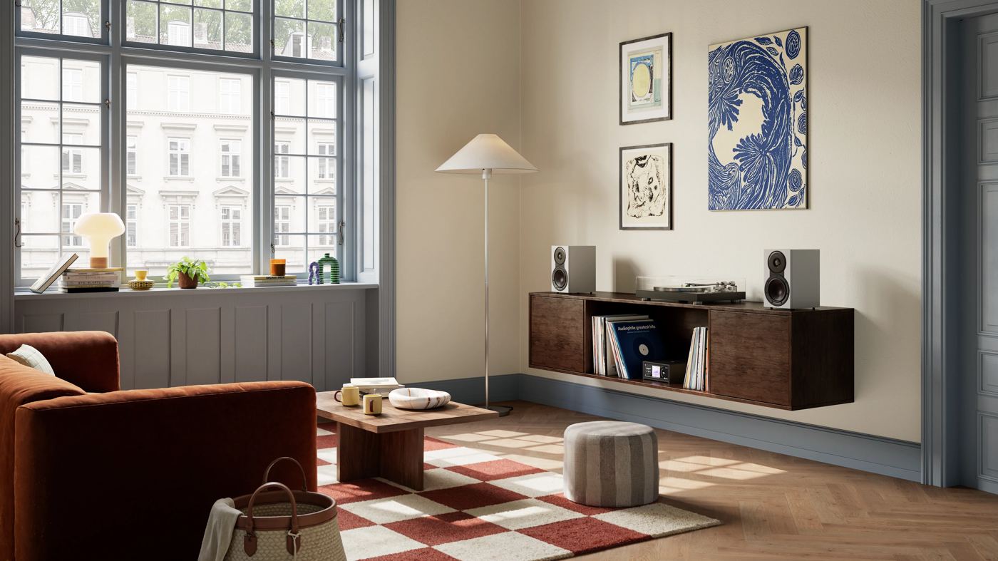Zwei Regallautsprecher auf einem Sideboard in einem hellen Wohnzimmer